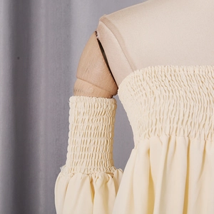 Detail showing the smocked elastic texture and puffed lantern sleeves of this yellow top