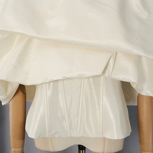 Detail of cream white satin corset top showing fishbone support and glossy fabric texture