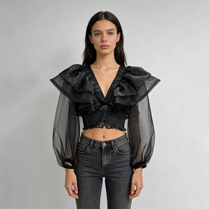 Dettaglio del crop top con scollo a V con volant e maniche lunghe in mesh trasparente