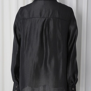 Detail of black satin shirt back featuring a vertical box pleat and elegant draping effect
