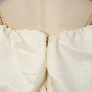 Detailed close-up of cream satin corset top featuring a metallic front zipper and pearly texture