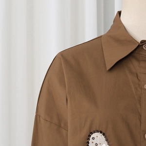 Detail of dark brown cotton shirt showing pointed collar and sequined chest embroidery