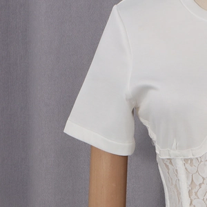 Dettaglio del top bianco a maniche corte con vita a corsetto in pizzo e design a pannelli