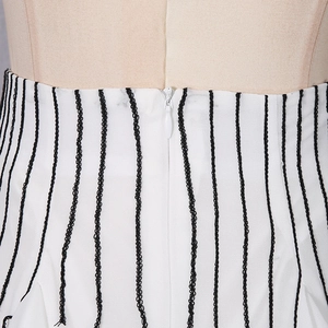 Detail of white midi skirt featuring black vertical textured stripes and a hidden back zipper