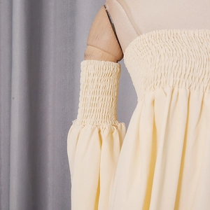 Detail of light yellow smocked dress bodice and puff sleeves on a wooden mannequin