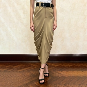 Close-up of khaki pleated midi skirt featuring a wide black leather belt and draping