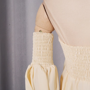 Close-up of smocked chiffon fabric and elastic ruffled sleeves on a beige top