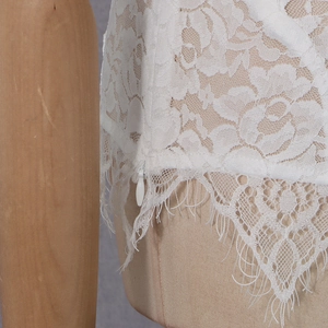 Dettaglio in pizzo floreale bianco con cerniera invisibile su un top aderente chic