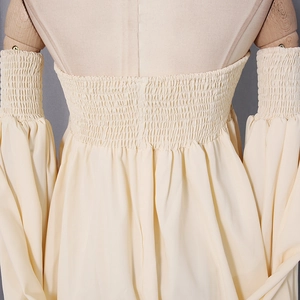 Detailed close-up of cream smocked blouse featuring elastic pleated texture and puff sleeves