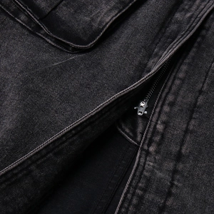 Dettaglio del denim nero lavato con cerniera in metallo e finiture con doppia cucitura