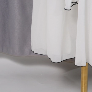 Detailed close-up of white mesh skirt featuring fine black contrast rolled hem stitching