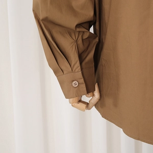 Close-up of brown casual shirt cuff featuring fine pleats and a matching button