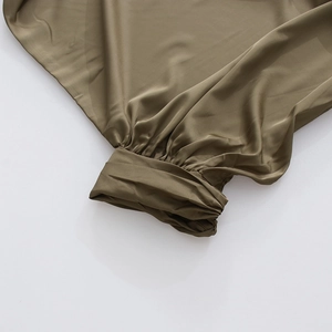 Détail du poignet en satin vert olive avec plis élégants et large bande de serrage