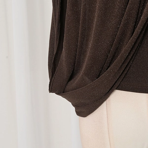 Detailansicht eines braunen Strickoberteils mit silbernem Glitzergarn und Faltenwurf