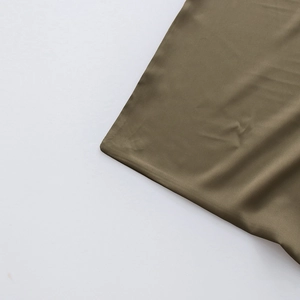 Détail de la texture satinée olive foncée et coutures lisses du pantalon style urbain