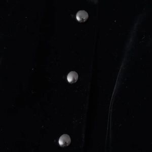 Detail view of silver metal buttons on black velvet fabric of the French style jacket