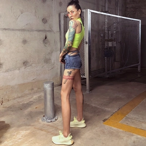 Detail von neongrünem Crop-Top und dunklen Denim-Shorts mit Taillenausschnitt und Schnürung