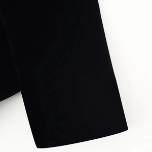 Detail of the sleeve cuff on a black velvet jacket featuring delicate fabric texture