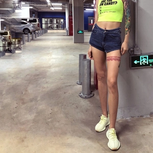 Eng anliegendes neongelbes Crop-Top mit High-Waist-Denim-Shorts und Schnürdetail
