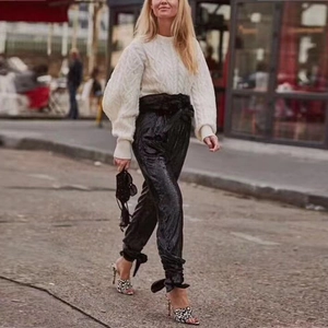 Pantaloni da donna con paillettes nere a vita alta con fiocco e maglione bianco a trecce