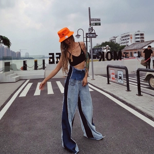 Detail of high-waisted patchwork denim flares with raw edges and wide-leg silhouette