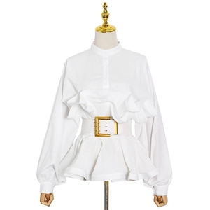 Detail view of white stand collar shirt with pleated layers and gold buckle belt