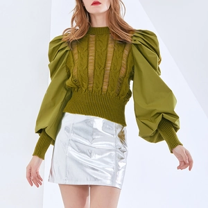 Detail of olive green cable-knit top with lantern sleeves and metallic silver skirt