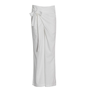 Détail de la taille haute croisée avec un grand nœud sur le pantalon blanc à jambes larges