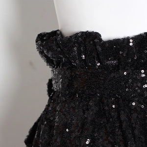 Dettaglio di volant in vita e paillettes nere su pantaloni casual da donna