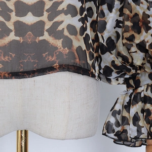 Macro detail of leopard print sheer chiffon fabric with puff sleeves and elastic frill cuffs