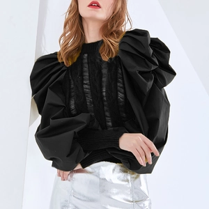 Detail of black knit top with textured bodice and dramatic puffy woven sleeves