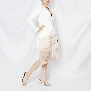 Detail view of white blazer dress showing gold embroidery and pink fringe tassels at the hem