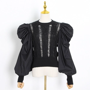 Detail of black knit top featuring hollow-out texture and voluminous puff sleeves