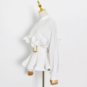 Detail of white ruffled shirt featuring pleated peplum hem and gold buckle waist belt
