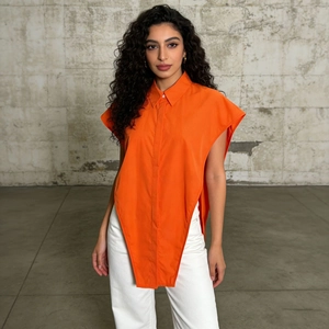 Detail of a bright orange sleeveless asymmetric shirt featuring a unique pointed hem design