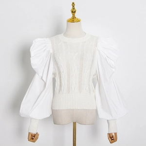 Detail of white cable knit top showing puffed sleeves and intricate stitch texture