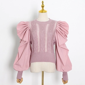 Detail of pink knit top featuring hollow-out patterns and exaggerated puff sleeves