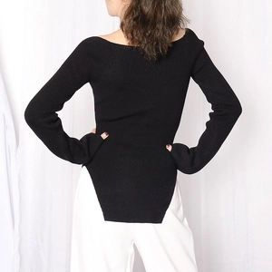 Detail of black ribbed knit sweater with unique side slit hem and long sleeve fit