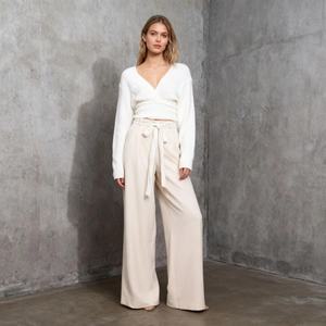 Detail of white V-neck wrap knit top paired with high-waisted belted cream trousers