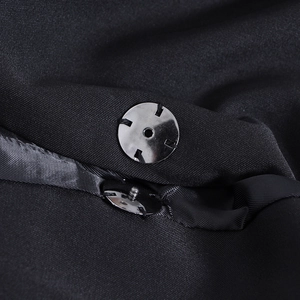 Macro shot of silver metal snap fastener and twill fabric texture on black blazer