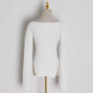 Detail of white ribbed knit sweater featuring side slits and a Bardot neckline style