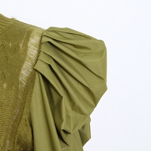 Detailed close-up of olive green knit fabric texture and pleated puff sleeve design