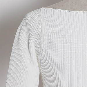 Detailed macro shot of white ribbed knit fabric showing neck line and shoulder texture
