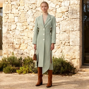 Detail of light green trench coat featuring hollow-out waist and white decorative buttons