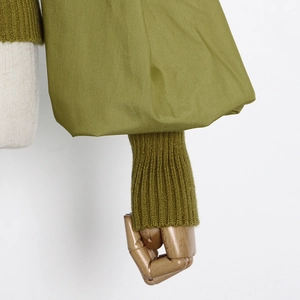 Detail of olive green knit top with lantern sleeves and ribbed cuffs on a mannequin
