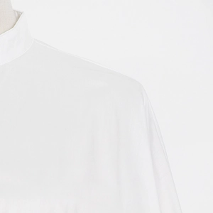 Detail shot of a white stand-collar shirt showing pleated ruffles and fine fabric texture