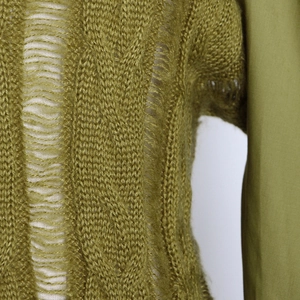 Detail of olive green cable-knit sweater featuring distressed rips and textured stitching