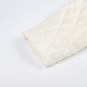 Detailed view of cream quilted jacket cuffs featuring classic diamond stitching pattern