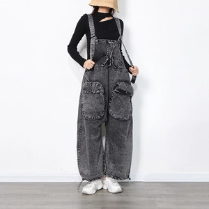 Détail d'une salopette en jean gris délavé avec grandes poches cargo et chevilles à cordon