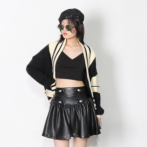 Détail de la mini-jupe noire en similicuir à taille haute avec nœuds en strass